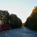a red semi truck driving down a curvy road