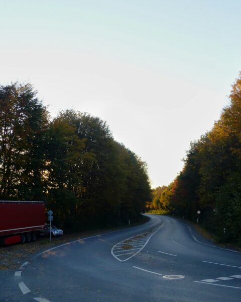 a red semi truck driving down a curvy road