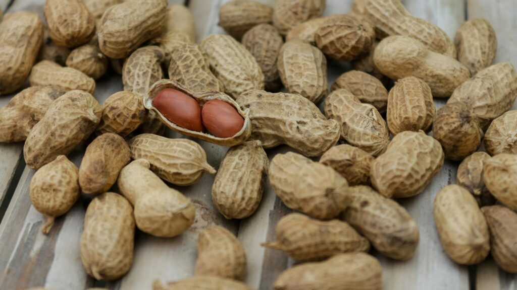 A detailed close-up of peanuts in their shells scattered on a wooden surface.
