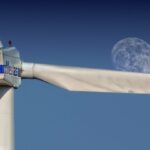 Wind turbine blades with moon backdrop, highlighting renewable energy aesthetics.
