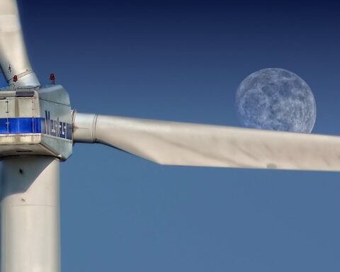 Wind turbine blades with moon backdrop, highlighting renewable energy aesthetics.