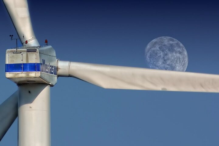 Wind turbine blades with moon backdrop, highlighting renewable energy aesthetics.