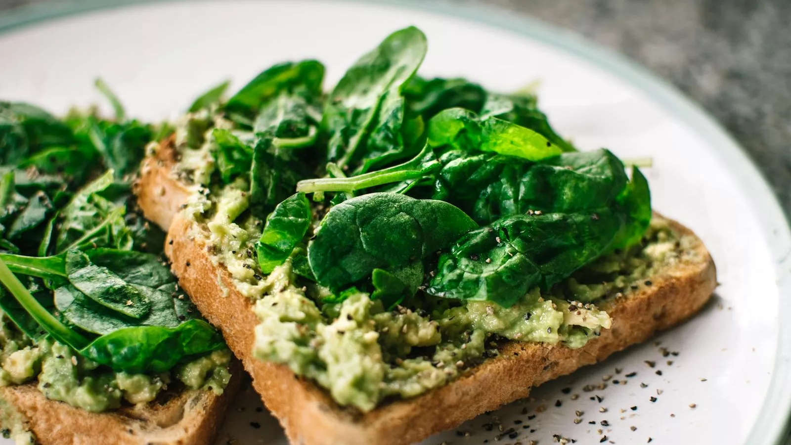 Close-up of a homemade avocado and spinach sandwich on whole grain toast.