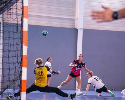 Dynamic action shot of a women's handball match with players in mid-movement.