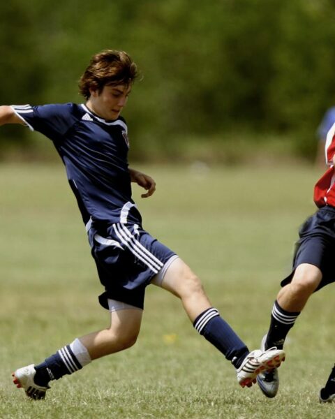 Teenage soccer players in action during an outdoor match showcasing skill and competition.