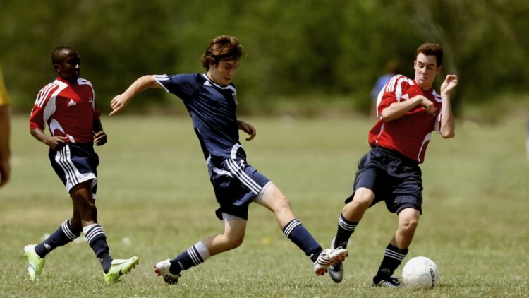 Teenage soccer players in action during an outdoor match showcasing skill and competition.