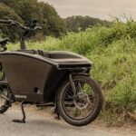 Vintage black cargo bike parked by grassy roadside in Düsseldorf, Germany.