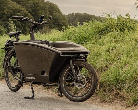 Vintage black cargo bike parked by grassy roadside in Düsseldorf, Germany.