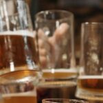 Group of friends clinking beer mugs, enjoying a fun gathering indoors.