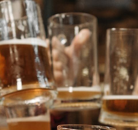 Group of friends clinking beer mugs, enjoying a fun gathering indoors.