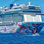 A colorful cruise ship sailing on the open sea under a clear blue sky. Ideal for tourism and travel themes.