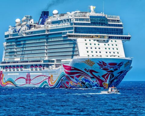 A colorful cruise ship sailing on the open sea under a clear blue sky. Ideal for tourism and travel themes.