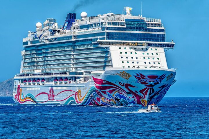 A colorful cruise ship sailing on the open sea under a clear blue sky. Ideal for tourism and travel themes.