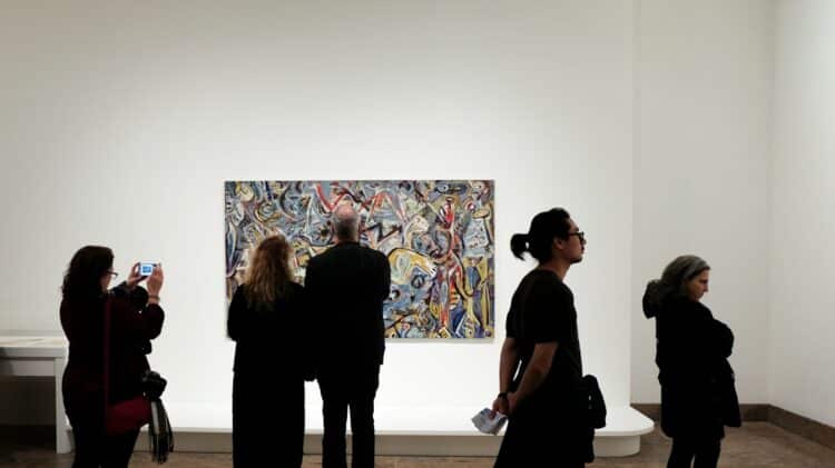 a group of people standing in front of a painting