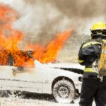 firefighter fighting burning car