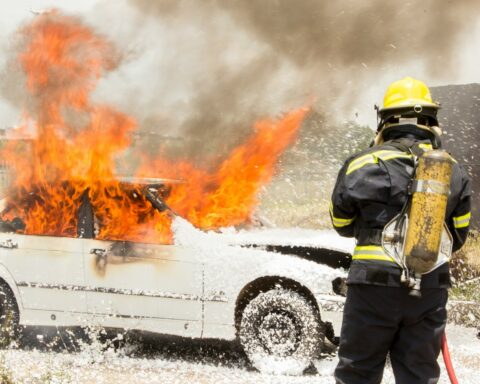 firefighter fighting burning car