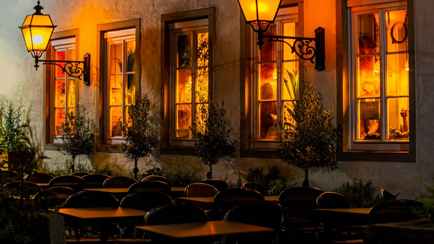 A row of tables sitting outside of a restaurant at night